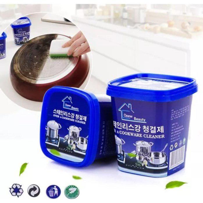 A blue container of Barrity/Korean Style Beauty Oven & Cookware Cleaner with its lid and label visible, set against a kitchen backdrop with a pot and stove.